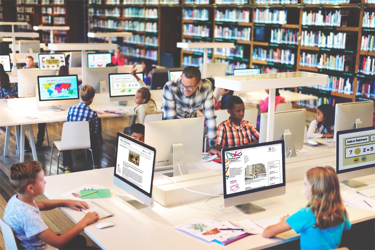 Kinder sitzen in einer Bibliothek an Computern