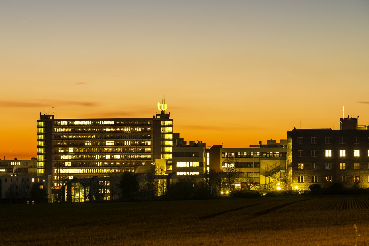 Beleuchtetes Gebäude der Technischen Universität Dormund in der Abenddämmerung.