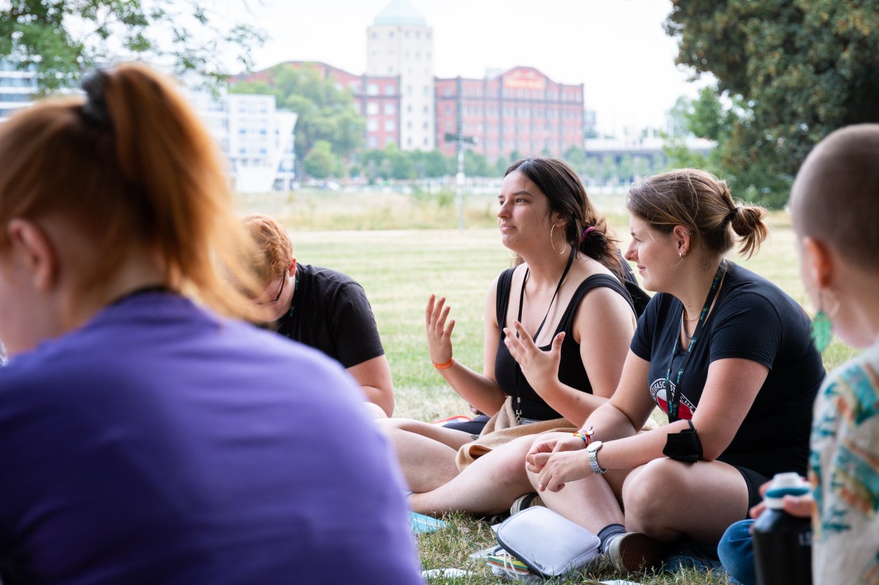 Teilnehmer*innen der Jugendkonferenz youcoN diskutieren in einem Park.