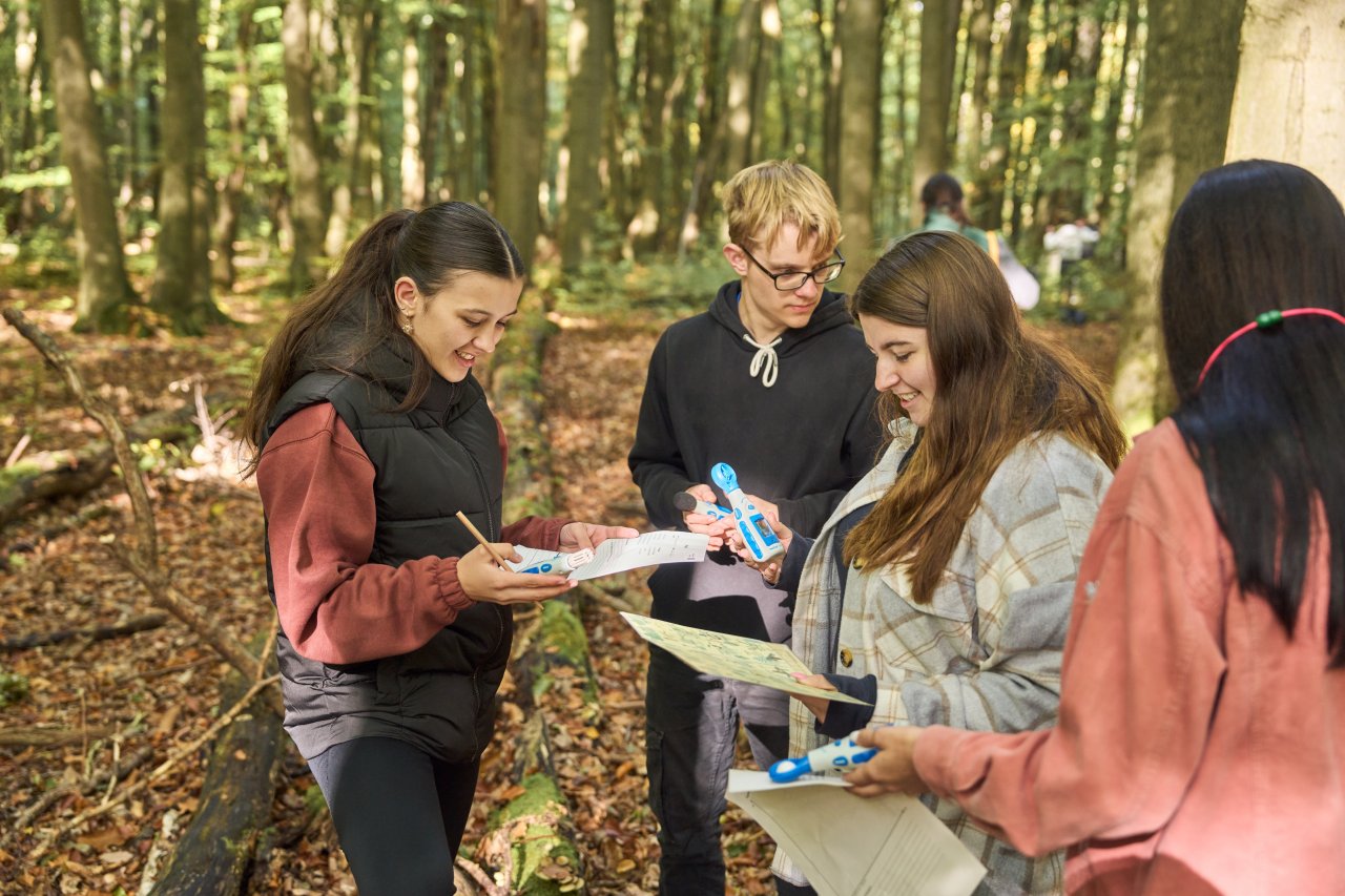 4 Schülerinnen und Schüler arbeiten in Kleingruppen zum Thema Ökosytem Wald. Die führen dabei unterschiedliche Messungen durch und bestimmen die Pflanzen des Nationalparks Hainich.