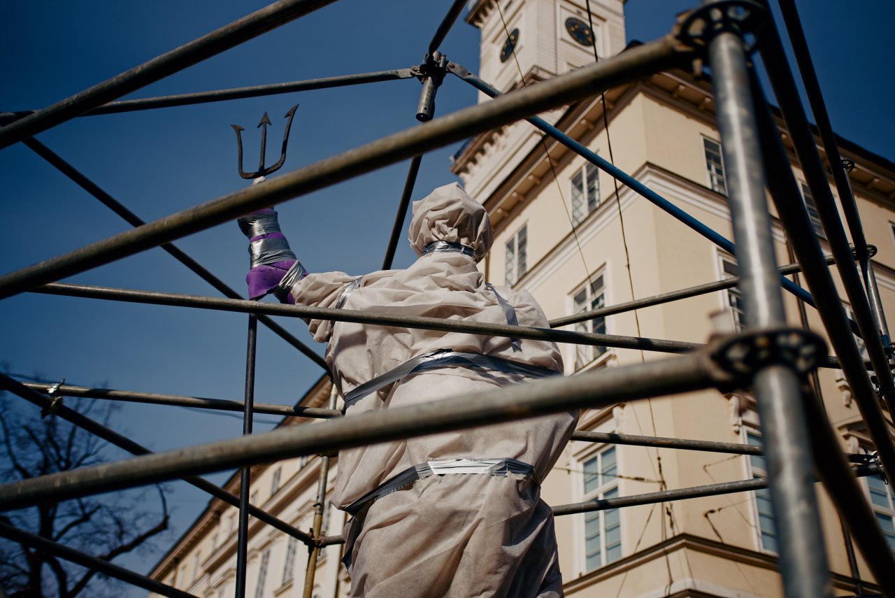 Die zum Schutz vor Angriffen in Decken gehüllte und von einem Gerüst umgebene Neptun-Statue in Lwiw.