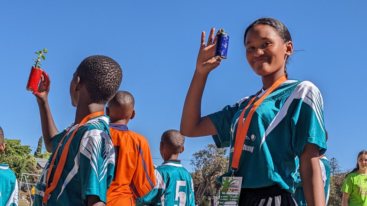 Kinder zeigen Stolz ihre gepflanzten Setzling beim Sportturnier