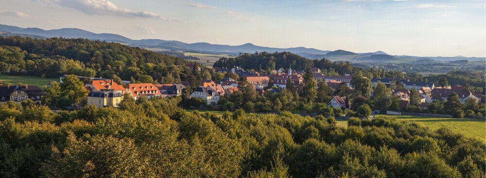 Panorama der Stadt Herrnhut mit Gebirgszug im Hintergrund.