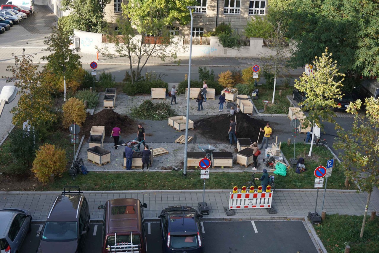 Auf einem Parkplatz werden Hochbeete aufgebaut.
