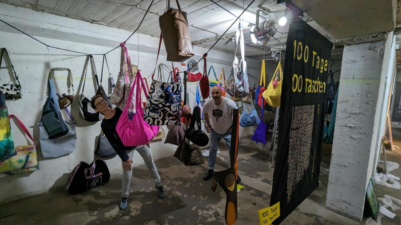 100 Tage 100 Taschen - Katrin Haller Leiterin der Modewerstatt (links) und Olivér Szabó (rechts) Organisation und Konzept der Kunstaustellung. Auf dem Bild zu sehen ein Teil der 100 diversen Upcycling Taschen die in der Modewerkstatt der JVA Köln Ossendorf genäht und gestaltet wurden. Die Ausstellung fand in einem alten Luftschutzbunker in Köln statt.