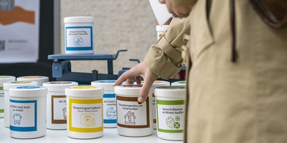 Klimawaage Dosen werden auf Waagschalen gelegt