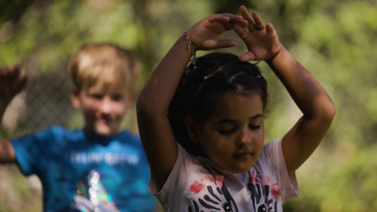 Zwei Kinder heben die Arme und bewegen sich, als wären sie ein Baum