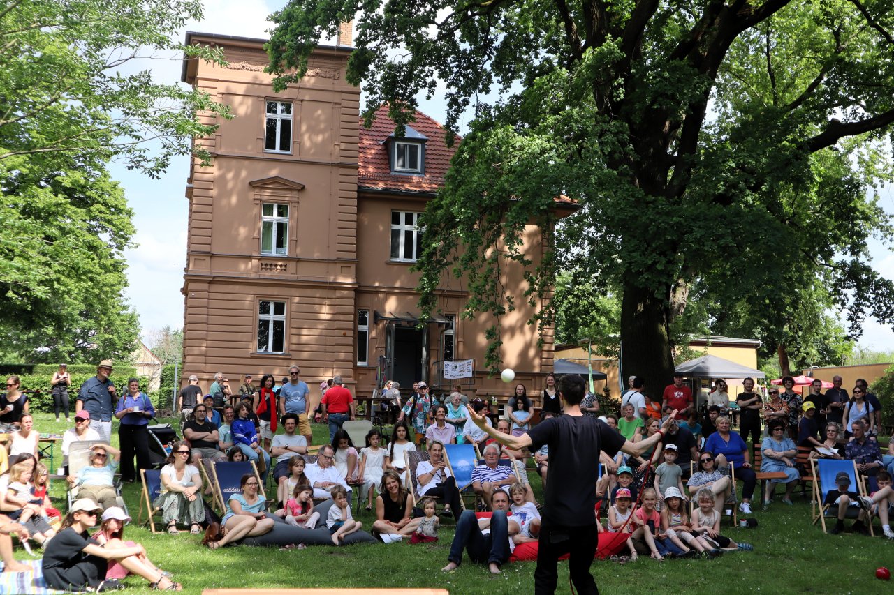 Viele Menschen im Garten der Villa Fohrde schauen einer jonglierenden Person zu