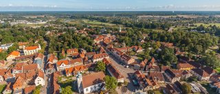 Vogelperspektive auf ein kleines Dorf. Das Dorf liegt im Grünen und alle Dächer sind aus roten Tonziegeln.