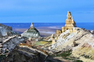 Landschaftsaufnahme - Im Vordergrund Felsen mit verschiedenfarbigen Gesteil und im Hintergrund Weite.