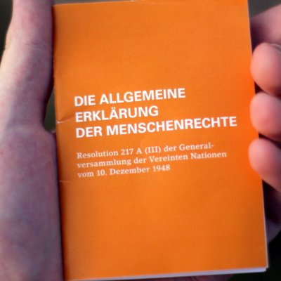 Hand hält die "Allgemeine Erklärung der Menschenrechte"