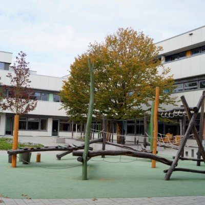 Spielplatz und Bäume vor dem Schulgebäude