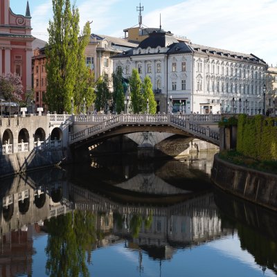 Blick auf drei Brücken über den Fluss Ljubljanica entlang der Altstadt Ljubljanas.