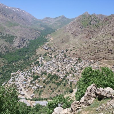 Eine trockene Berglandschaft, deren Hänge von kleinen Steinhäusern und einigen Bäumen gesäumt werden.