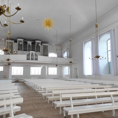 Der Kirchsaal der Brüdergemeine. Die Einrichtung ist aus weißem Holz: Kirchbänke, Empore und Orgel.